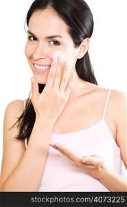 A beautiful hispanic woman applying lotion to her face in the bathroom