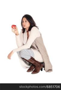 A beautiful Hispanic woman crouching on the floor holding a red apple,isolated for white background.