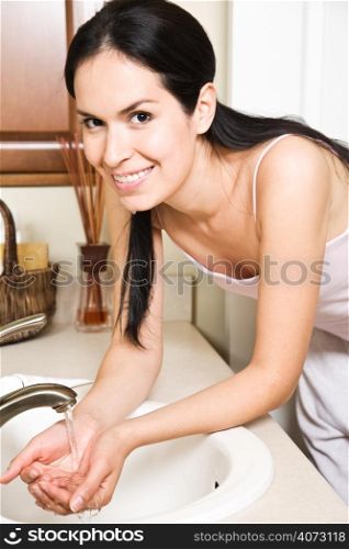 A beautiful hispanic woman washing her face in the bathroom