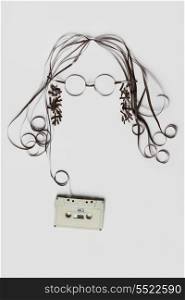 A beautiful image made of tape cassette with the tape forming a face of hair glasses on bright background.