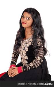A beautiful Indian woman in a native black dress and long black hairsitting on a chair, isolated for white background.