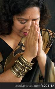 A beautiful Indian woman wearing a traditional sari and praying.