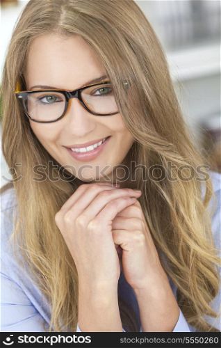 A beautiful intelligent blond girl or young woman looking happy and wearing geek glasses