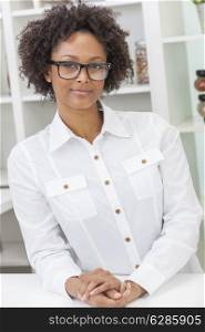A beautiful intelligent mixed race African American black girl or young woman looking happy and wearing geek glasses in kitchen at home