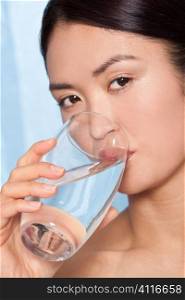 A beautiful Japanese Asian woman drinking a glass of pure clear mineral water