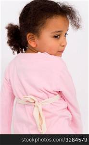 A beautiful little mixed race girl dressed in pink looks back over her shoulder