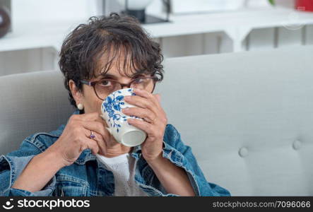 a beautiful mature brunette drinking a tea at home