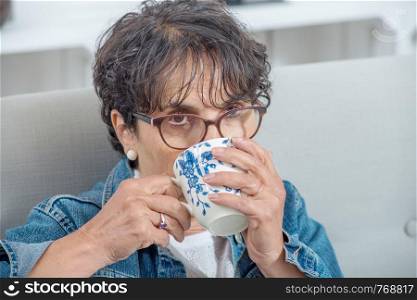 a beautiful mature brunette drinking a tea at home