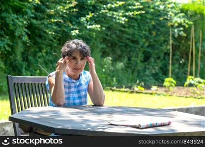 a beautiful middle-aged woman has a headache in the garden