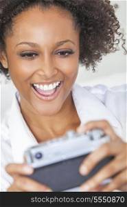 A beautiful mixed race African American girl or young woman laughing and taking a selfie picture on a retro style digital camera