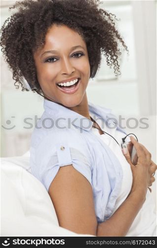 A beautiful mixed race African American girl or young woman laughing with perfect teeeth and listening to music on mp3 player and headphones