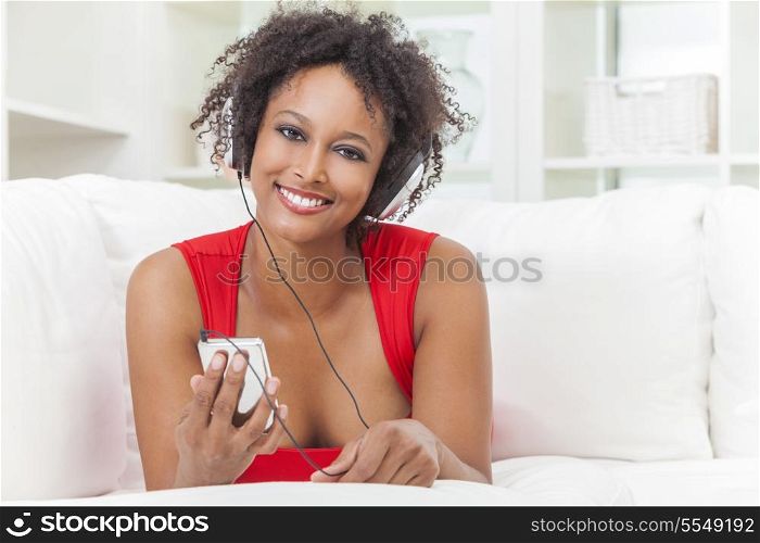 A beautiful mixed race African American girl or young woman laying down wearing a red dress listening to music on mp3 player and headphones