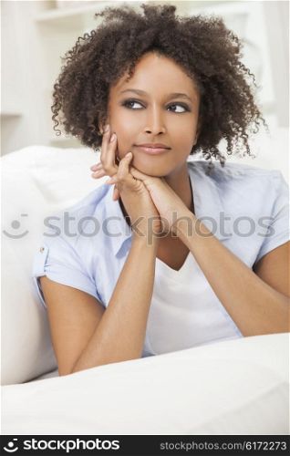 A beautiful mixed race African American girl or young woman laying down on sofa at home looking thoughtful and relaxed