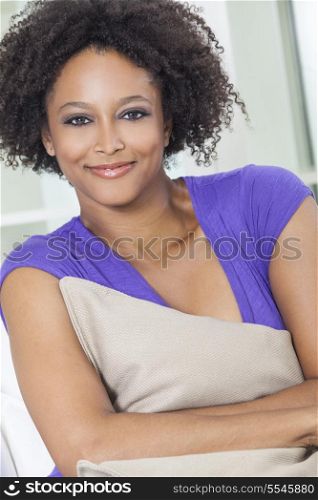 A beautiful mixed race African American girl or young woman looking happy and thoughtful holding a cushion
