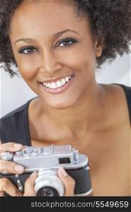 A beautiful mixed race African American girl or young woman looking happy taking pictures or photographs with a retro digital camera