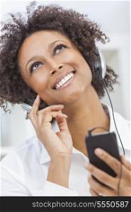 A beautiful mixed race African American girl or young woman looking up &amp; listening to music on mp3 player and headphones