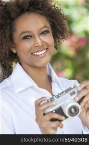 A beautiful mixed race African American girl or young woman outside looking happy taking pictures or photographs with a retro digital camera