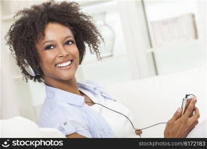 A beautiful mixed race African American girl or young woman relaxing at home listening to music on mp3 player and headphones