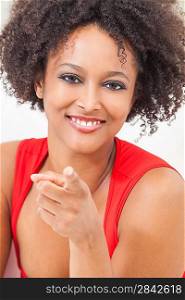 A beautiful mixed race African American girl or young woman wearing a red dress looking happy and pointing to camera