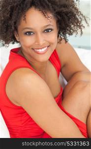 A beautiful mixed race African American girl or young woman wearing a red dress looking happy and smiling