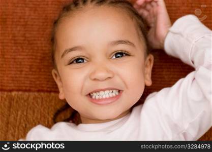 A beautiful mixed race girl smiles with great white teeth showing for the camera