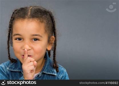 A beautiful mixed race girl with her finger to her lips and laughing