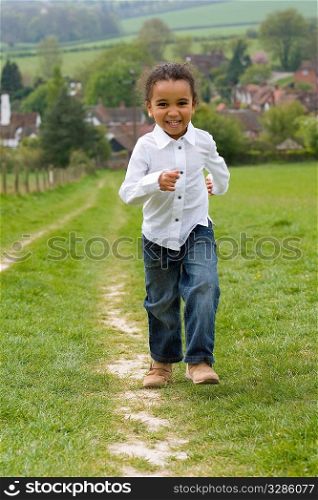 A beautiful mixed race little running up a hill in the English countryside and laughing