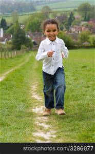 A beautiful mixed race little running up a hill in the English countryside and laughing