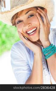 A beautiful mixed race young woman laughing and having fun wearing a straw cowboy hat, shot under a palm tree on a tropical beach
