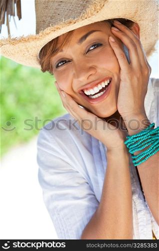 A beautiful mixed race young woman laughing and having fun wearing a straw cowboy hat, shot under a palm tree on a tropical beach
