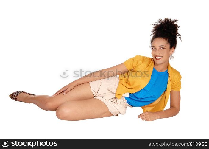 A beautiful multi-racial woman lying on her site on the floor in a yellow sweater and beige shorts with her curly black hair in a bun on her head,isolated for white background