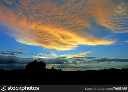A beautiful orange sunset with blue sky, fluffy clouds.