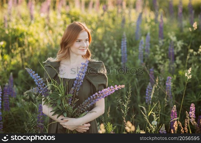 A beautiful red-haired girl in a thicket of lupine.. Portrait of a red-haired girl in a thicket of lupin 3272.