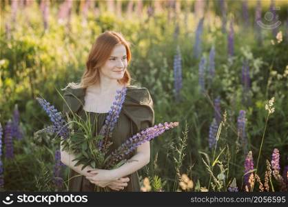 A beautiful red-haired girl in a thicket of lupine.. Portrait of a red-haired girl in a thicket of lupin 3272.