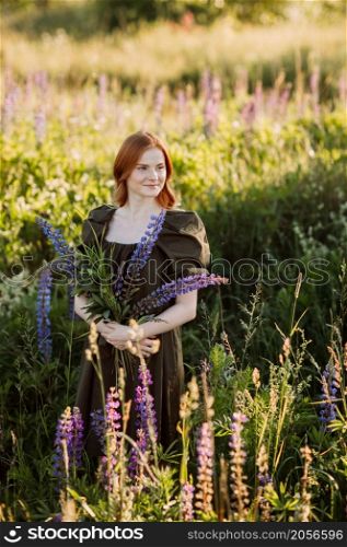 A beautiful red-haired girl in a thicket of lupine.. Portrait of a red-haired girl in a thicket of lupin 3273.