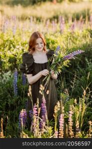 A beautiful red-haired girl in a thicket of lupine.. Portrait of a red-haired girl in a thicket of lupin 3274.