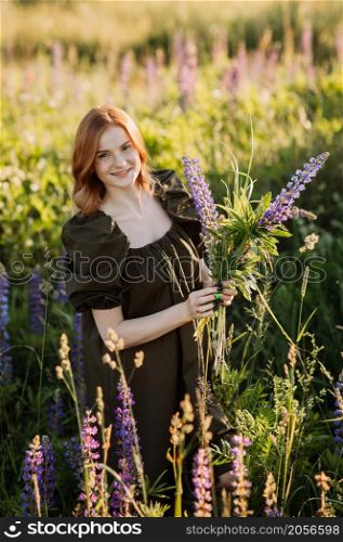 A beautiful red-haired girl in a thicket of lupine.. Portrait of a red-haired girl in a thicket of lupin 3275.
