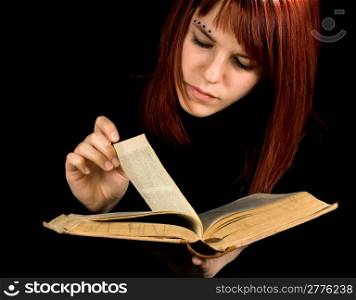 A beautiful redhead girl studying from a book. Studio shot.