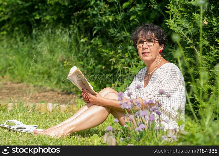 a beautiful senior woman reading a book in the garden