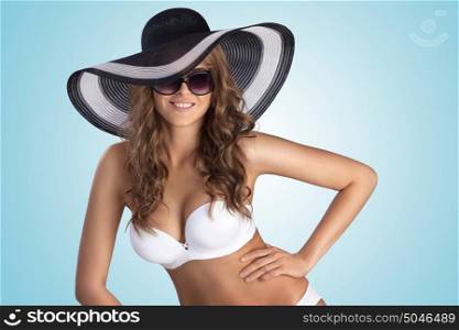 A beautiful sexy girl posing in white bikini and stylish sun hat.