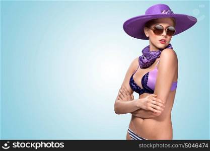 A beautiful sexy girl standing in violet bikini, stylish hat and sunglasses.