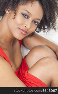 A beautiful sexy mixed race African American girl or young woman wearing a red dress looking happy and smiling
