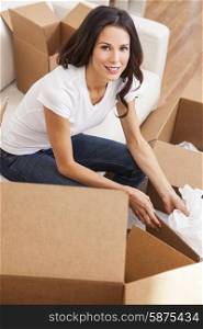 A beautiful single young woman packing or unpacking boxes and moving into a new house or home