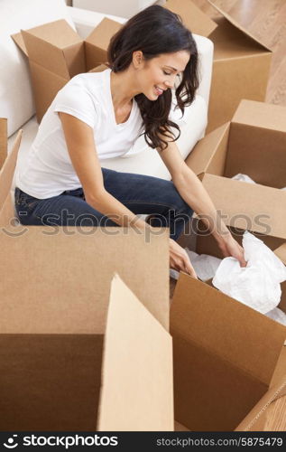 A beautiful single young woman packing or unpacking boxes and moving into a new house or home