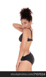 A beautiful slim young multi-racial woman standing in profile in a black bikini in the studio with her curly black hair in abun on her head, isolated for white background