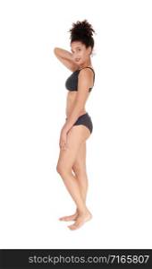 A beautiful slim young multi-racial woman standing in profile in a black bikini in the studio looking into camera, bare foot with her curly black hair in a bun on her head, isolated for white background