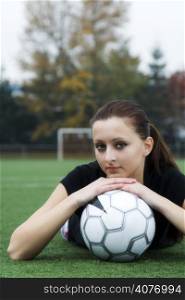 A beautiful soccer player resting on a soccer ball