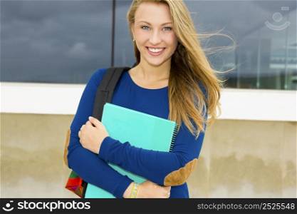 A beautiful student in the college holding a backpak and notebooks