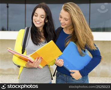 A beautiful student showing something on the books to anoither student