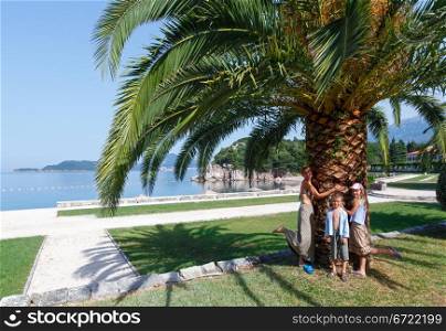 A beautiful summer park morning view near Milocer Beach and family near palm tree (Montenegro, Budva)